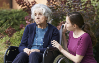 adult daughter comforting senior mother in wheelchair