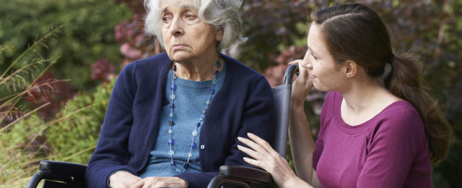 adult daughter comforting senior mother in wheelchair