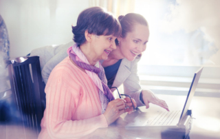 younger woman helping an elderly person using laptop computer for internet search. young and pension age generations working together.