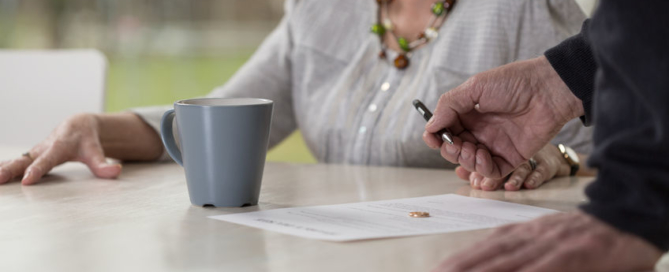 close-up of elder man signingdocuments