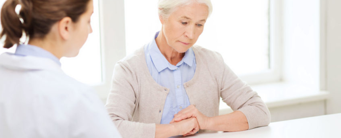 medicine, age, health care and people concept - doctor with clipboard and senior woman meeting at hospital