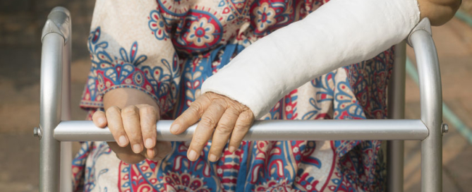 senior woman broken wrist using walker in backyard.