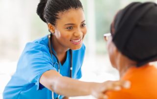 caring african medical nurse comforting senior patient in office