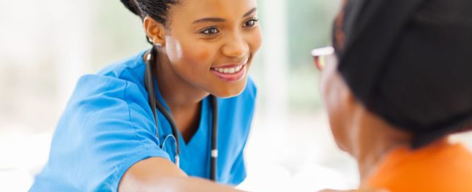 caring african medical nurse comforting senior patient in office