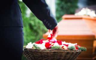 woman on funeral putting rose petals on coffin