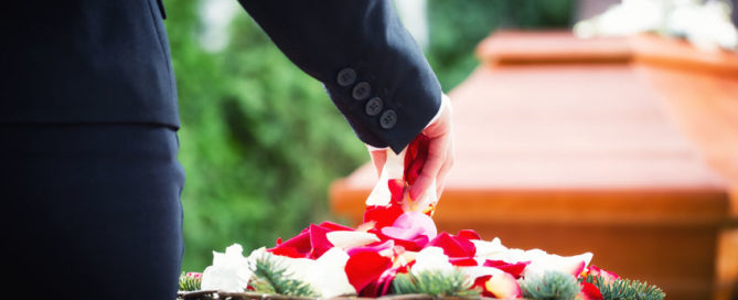 woman on funeral putting rose petals on coffin